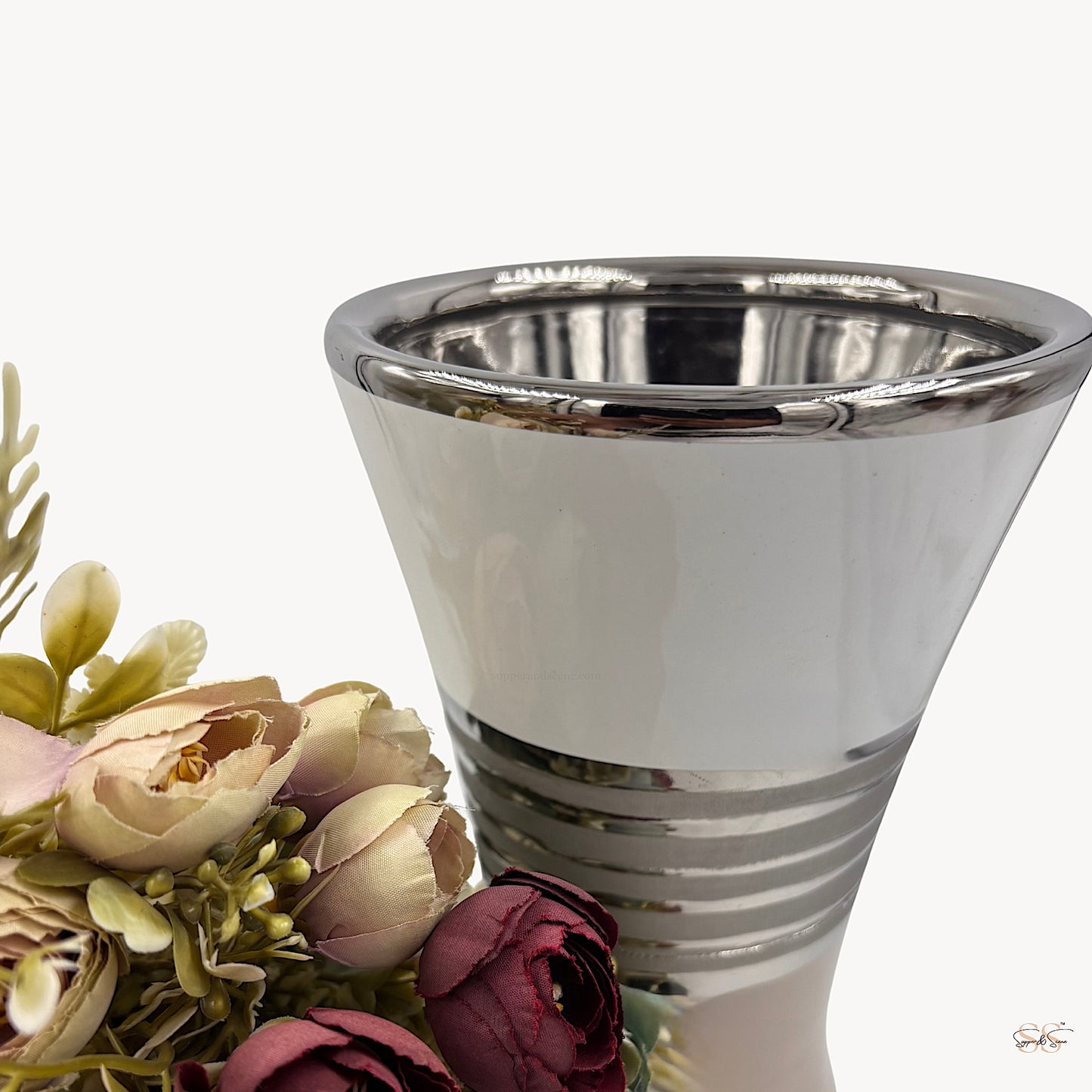 Close-up of a modern ceramic vase featuring a glossy white finish with silver lining details, styled with pastel artificial flowers by Supper & Scene.