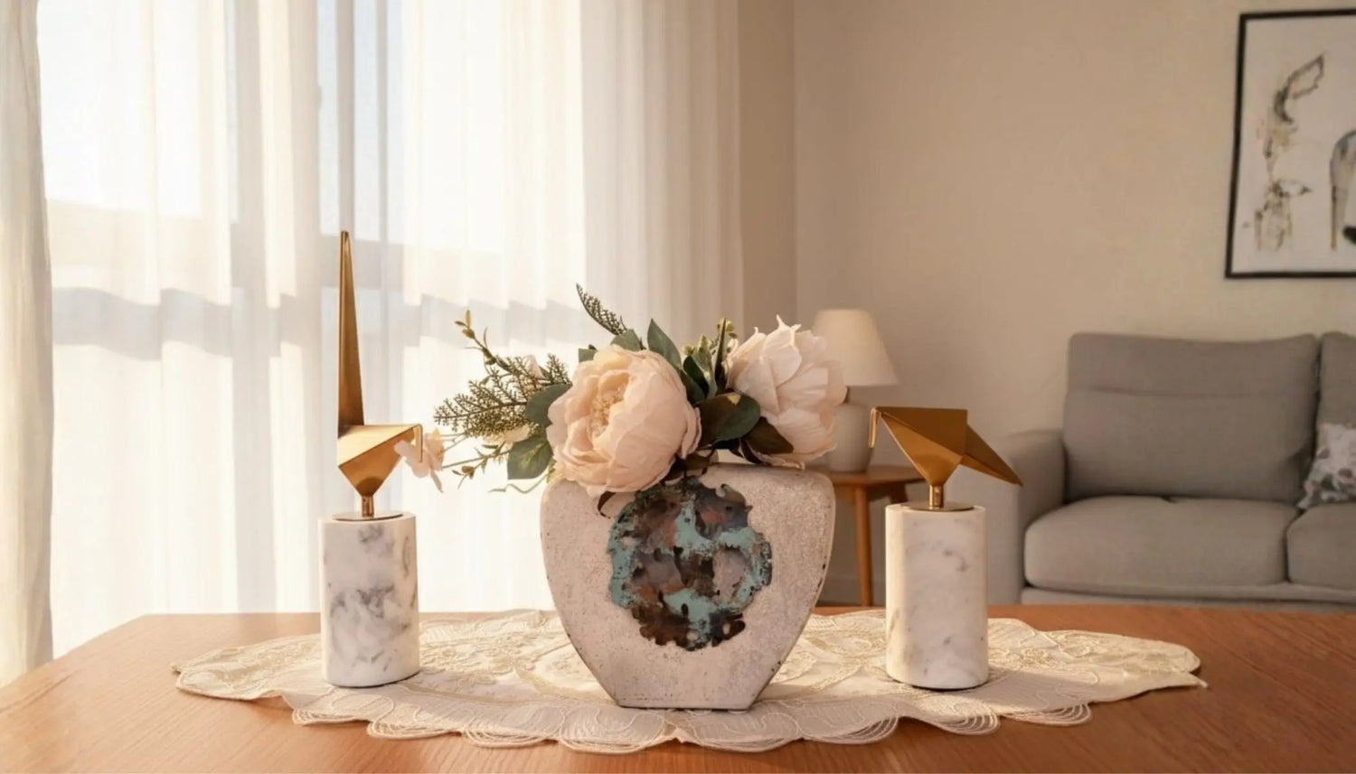 Decorative setup with a vase, candles, and flowers on a table in a living room.