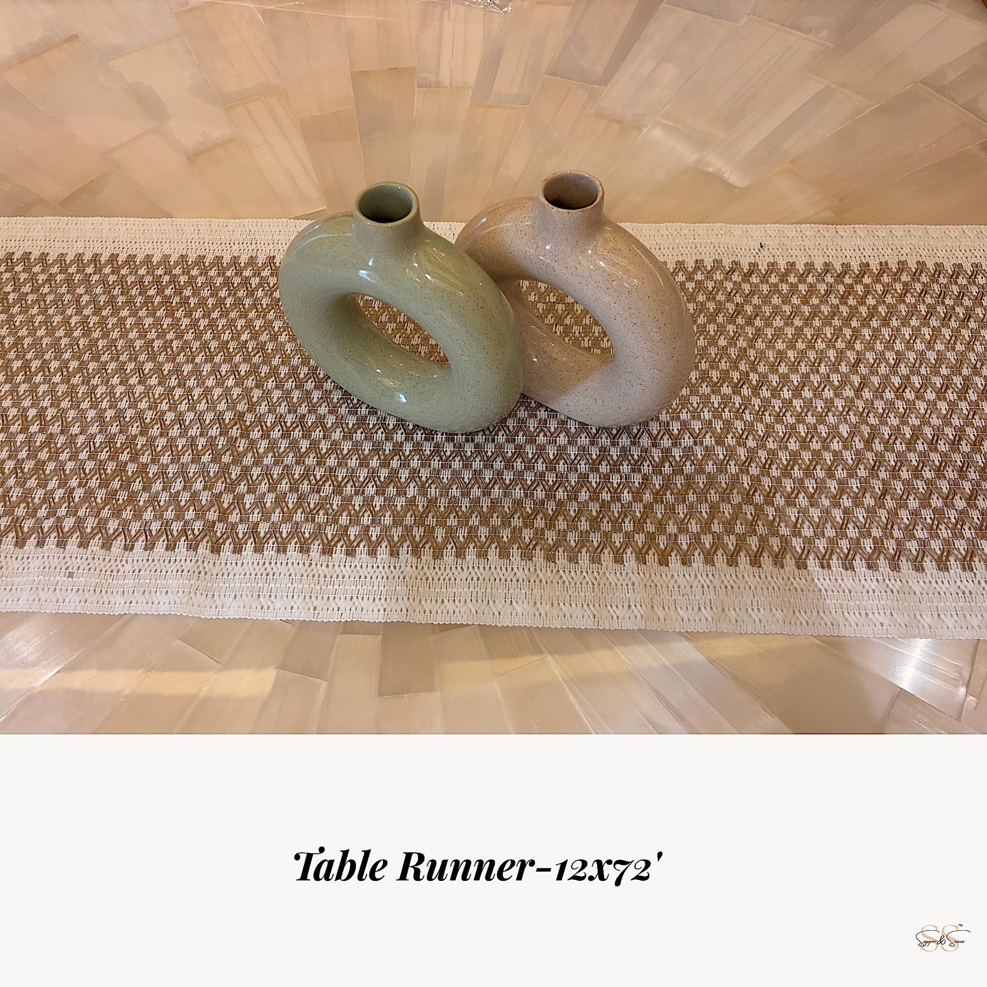 A beige and white woven table runner measuring 12x72 inches, styled with two donut-shaped ceramic vases placed at the center.