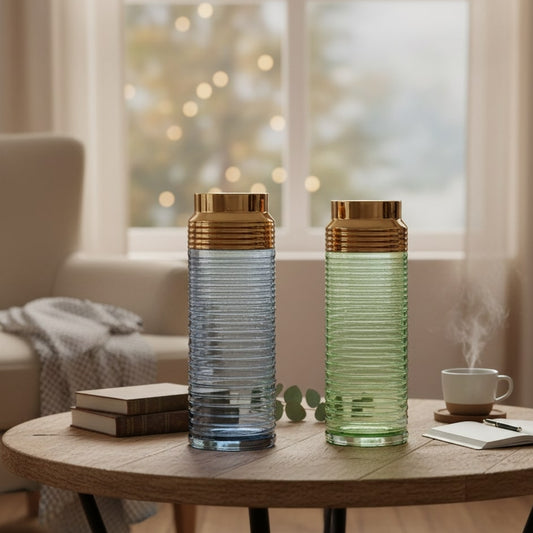 Two glass vases with gold bases on a wooden table in a living room.