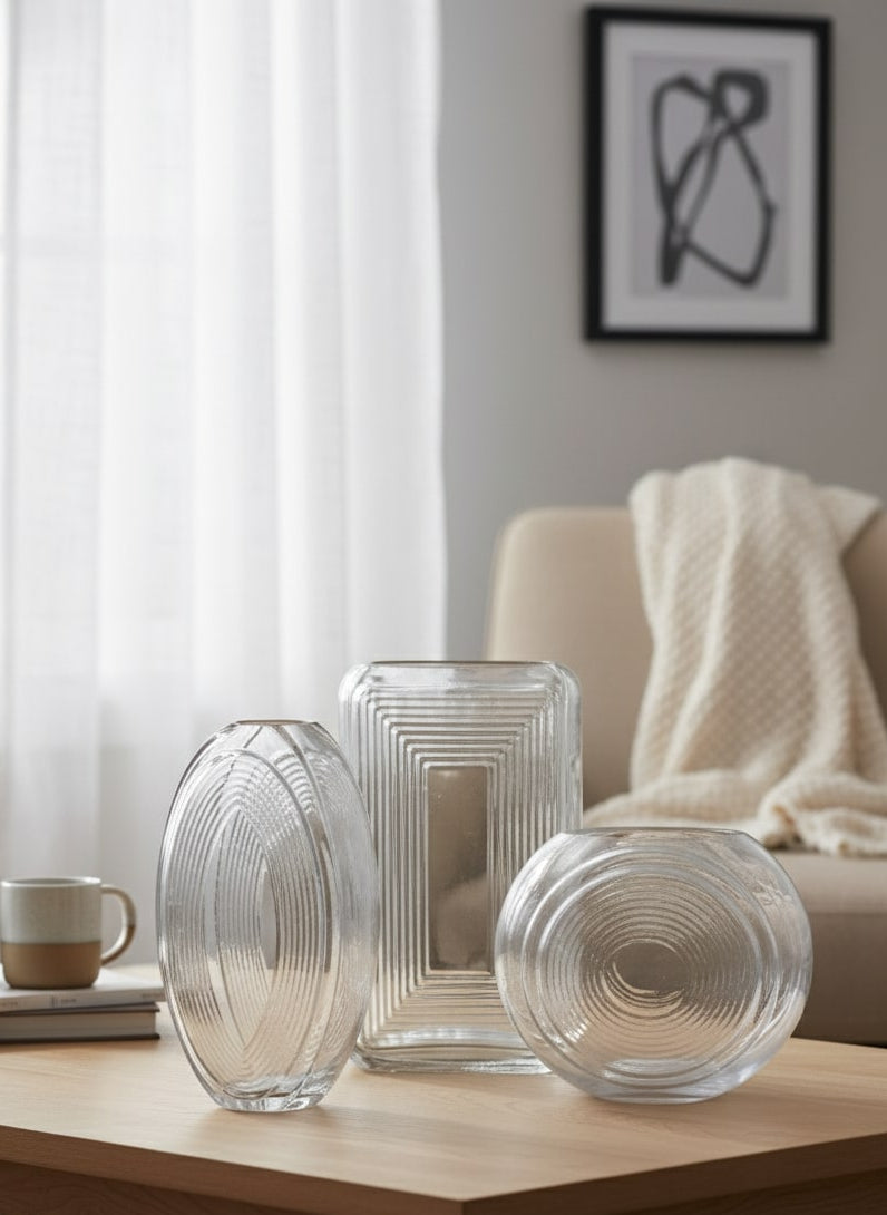 Three clear glass vases on a wooden table in a living room setting by supper and scene