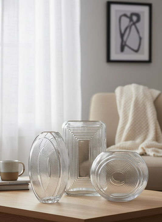 Three clear glass vases on a wooden table in a living room setting by supper and scene