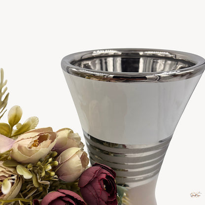 Close-up of a modern ceramic vase featuring a glossy white finish with silver lining details, styled with pastel artificial flowers by Supper & Scene.
