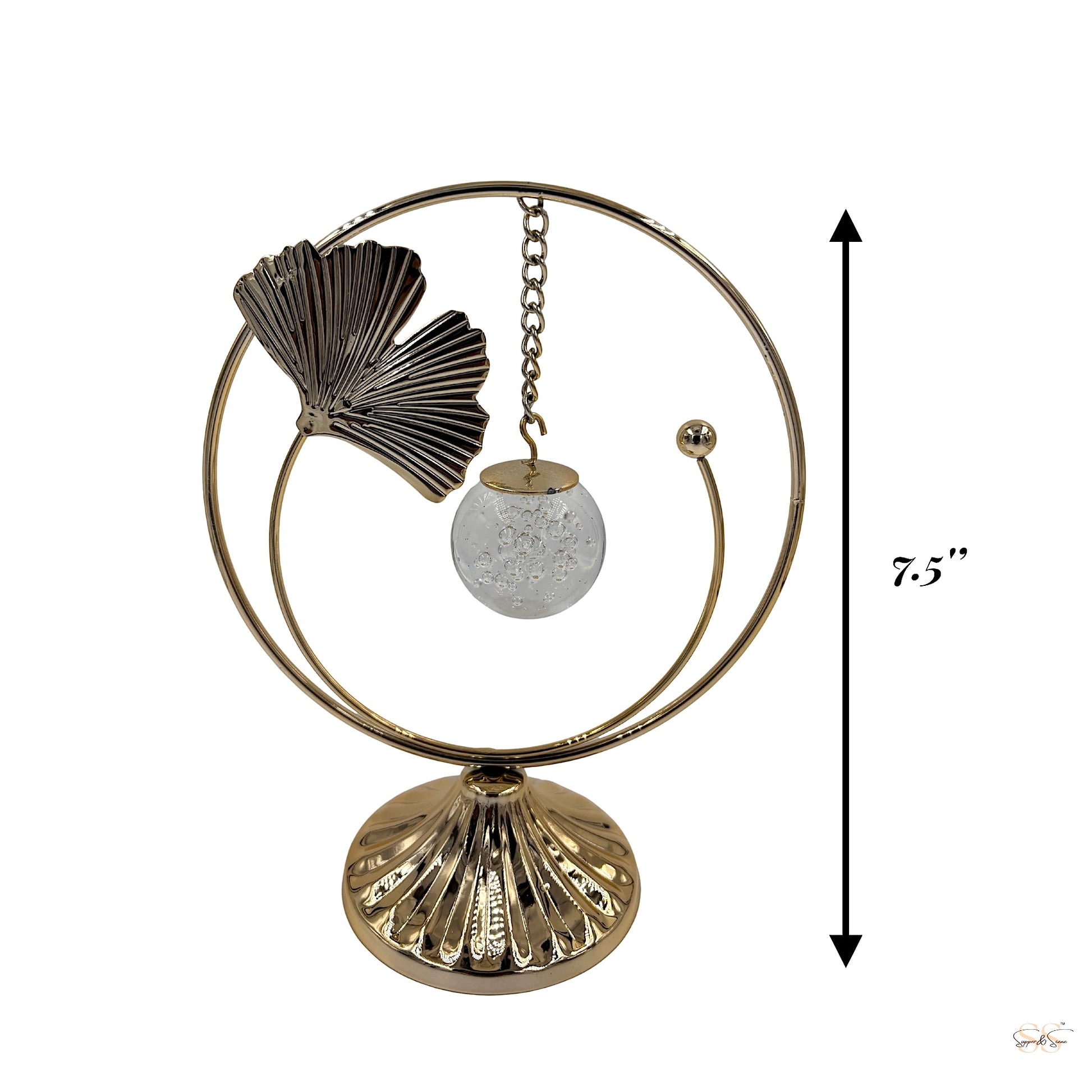 Gold decorative showpiece featuring a textured leaf accent and hanging crystal-like orb, styled with artificial flowers for modern interiors, by Supper & Scene.