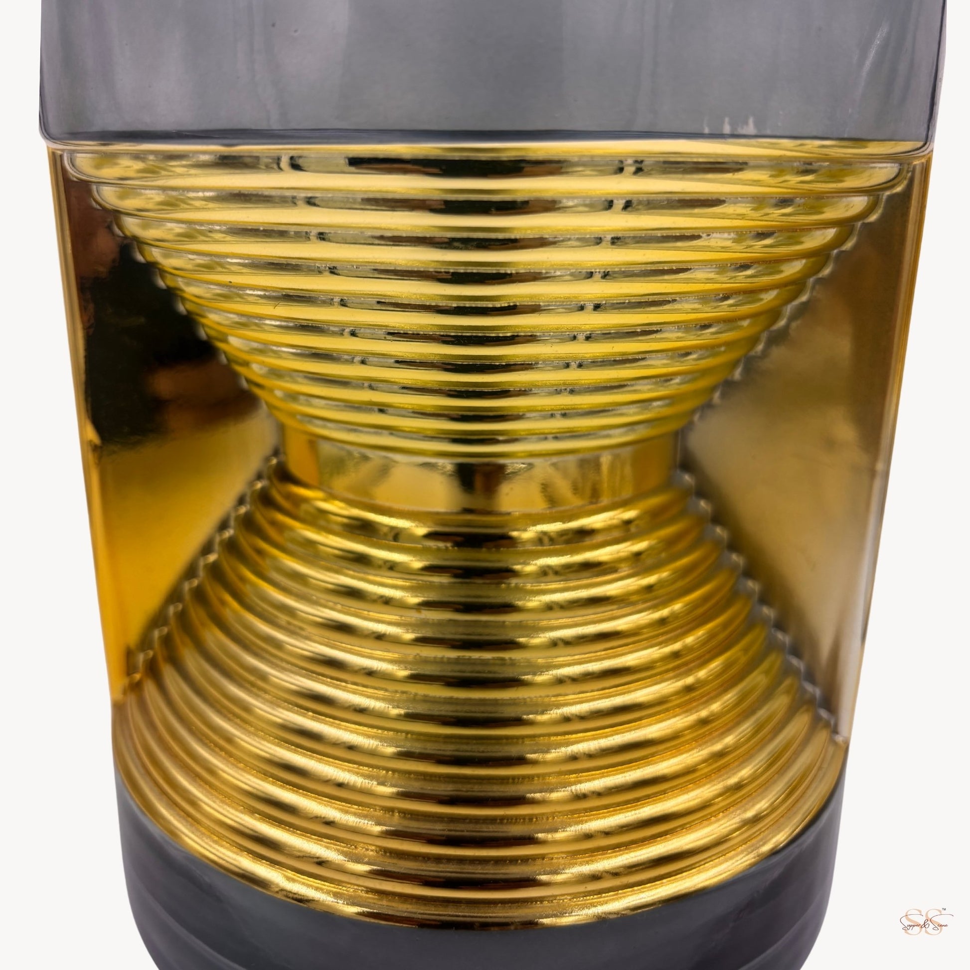 Close-up of a modern black and gold glass vase featuring a ribbed hourglass metallic design by Supper & Scene.