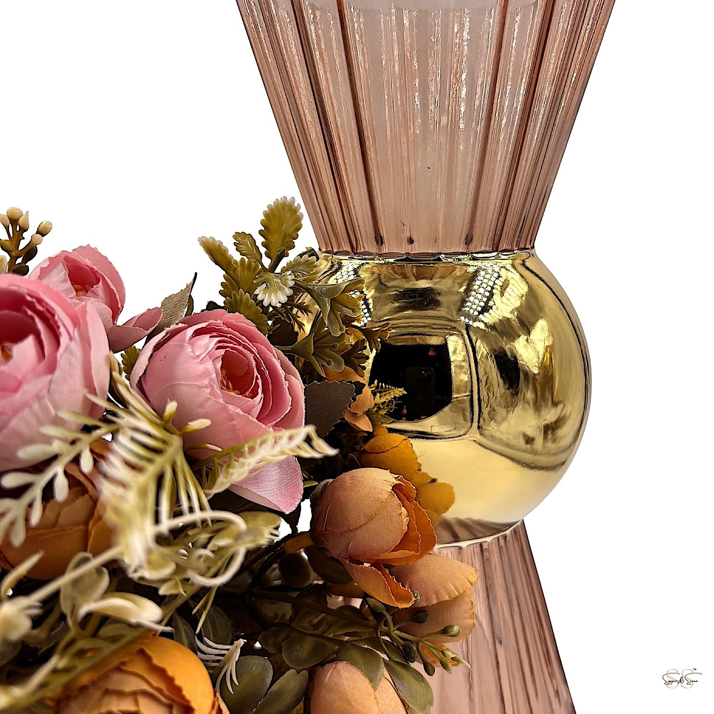 Pink ribbed glass vase with a reflective gold center sphere, styled with peach and pink artificial flowers around the base by Supper & Scene.