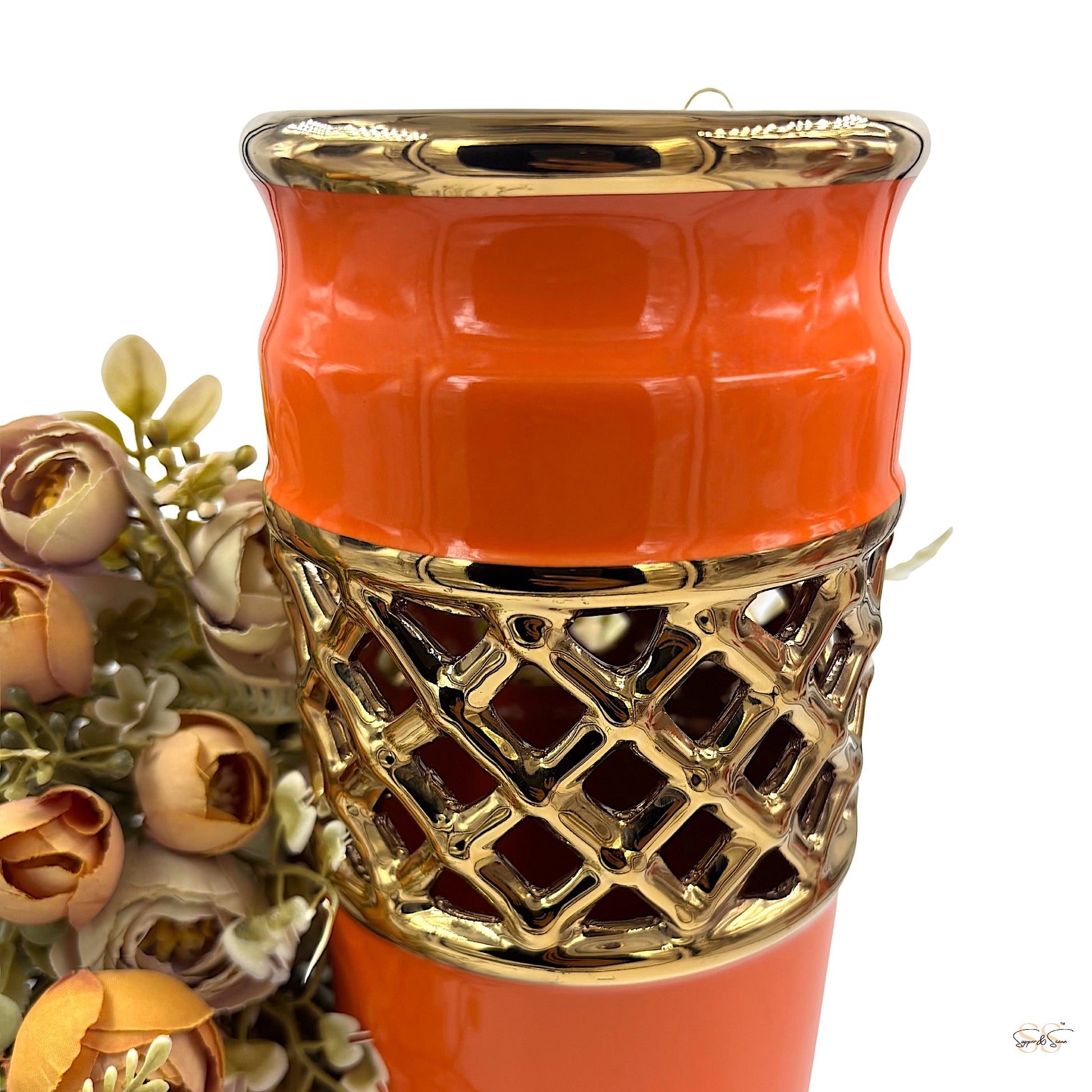 Close-up view of an orange ceramic vase with a gold lattice design and glossy finish.