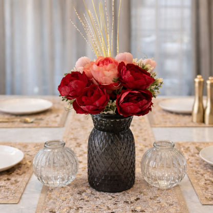 Floral arrangement in a black vase on a table with decorative elements