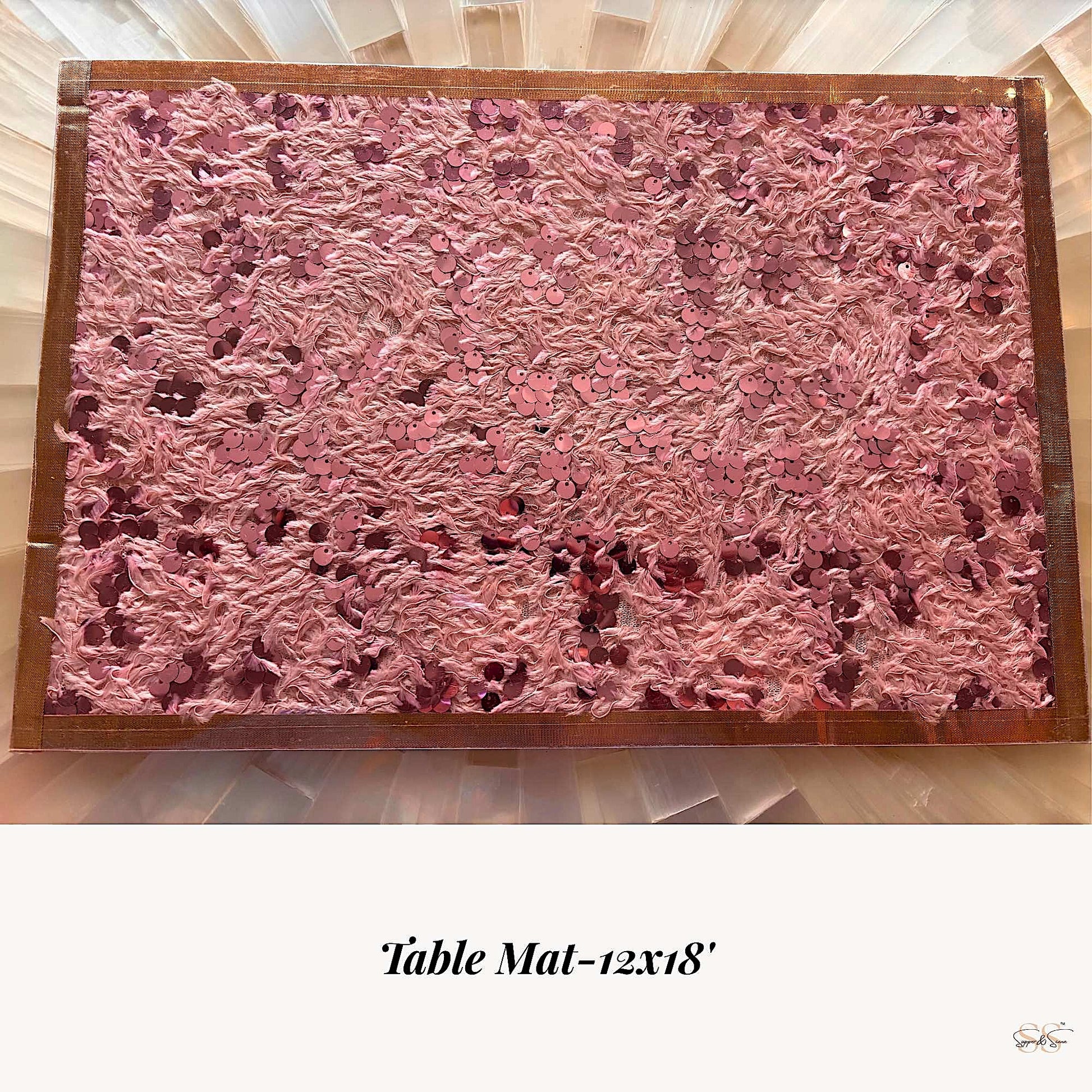 Pink textured table mat with sequins and gold edging displayed flat on a dining table, by Supper & Scene.