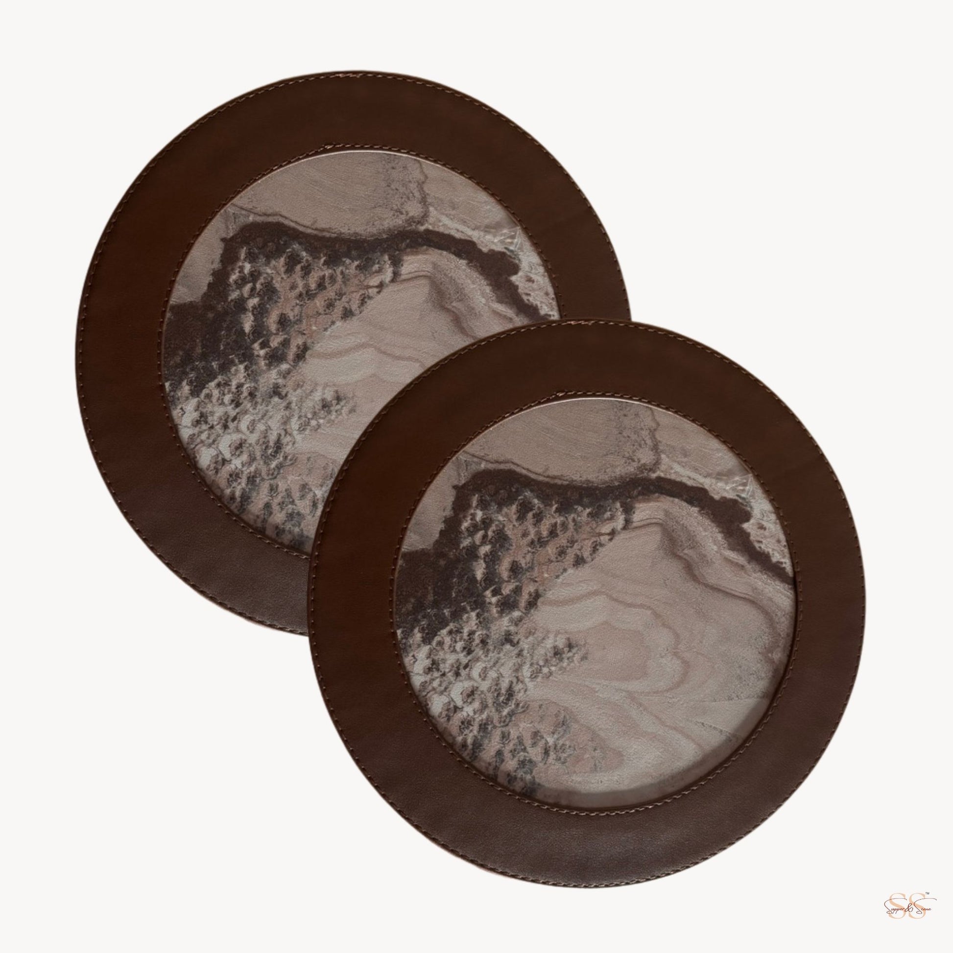 Two round trinklets with a marbled design and brown leather rim on a white background.