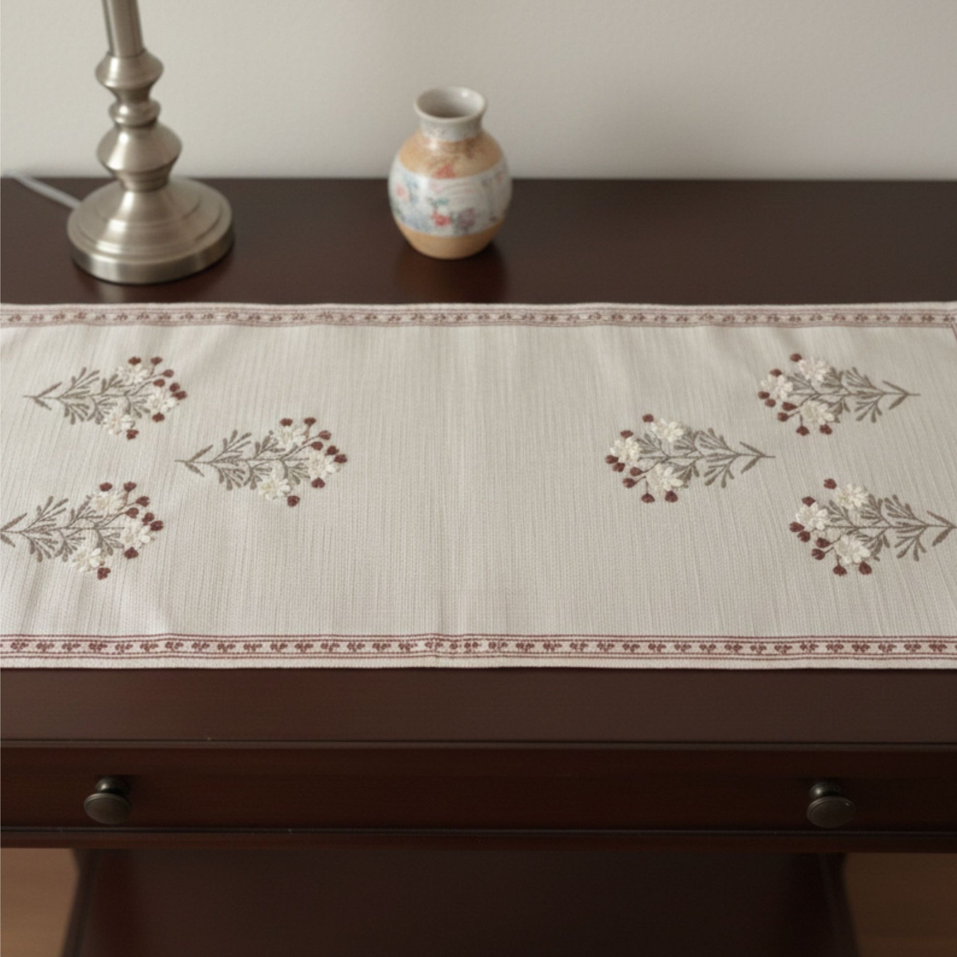 short brown embroidery table runner on console